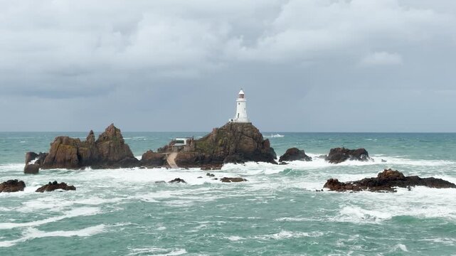 La Corbiere Lighthouse Jersey Channel Islands with rough water breaking over the rocks wild coastline