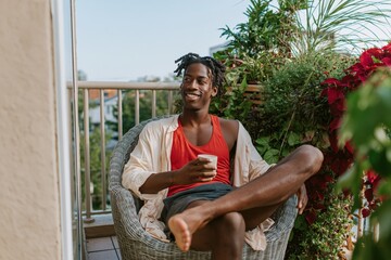Obraz premium Relaxed man on balcony with coffee and plants in morning for lifestyle background and banner use