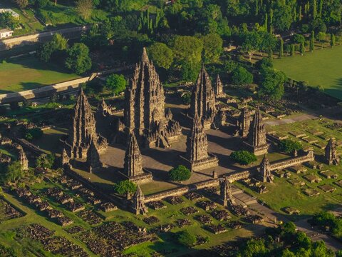 Aerial view of the ancient Prambanan Temple complex with its towering stone structures surrounded by lush green trees and lawns Kecamatan Prambanan, Daerah Istimewa Yogya, Indonesia.