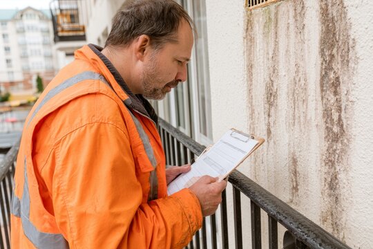 Building Inspector Checking Balcony Drainage Scupper After Rain
