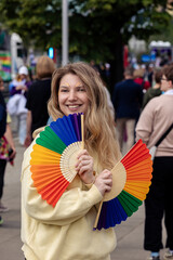 Young woman with rainbow folding fans at 25th Warsaw Equality Parade (Parada Równości). LGBTQ pride, diversity, equality and inclusion concept © Alina