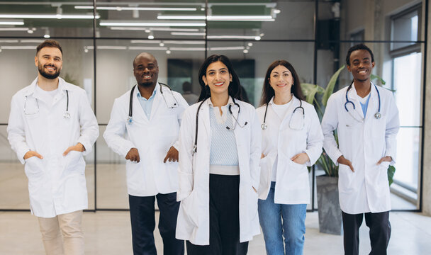 Diverse team of medical doctors standing in clinic, smiling at camera, showing unity and professional healthcare support