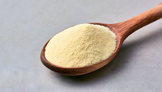 Found in a wooden spoon, xanthan gum powder is a fine yellow ingredient commonly used in baking and cooking. It's gluten-free, aiding in thickening and stabilizing dishes.