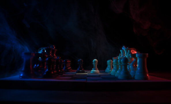 Chess board game concept of business ideas and competition. Chess figures on a dark background with smoke and fog.