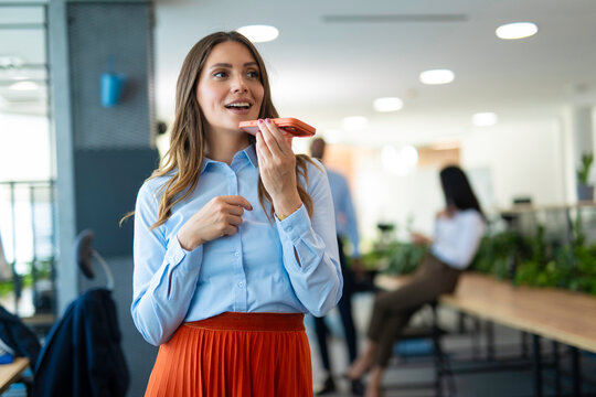 Businesswoman recording voice message on smartphone in office