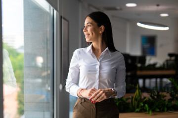 Fototapeta premium Businesswoman looking out office window dreaming career success