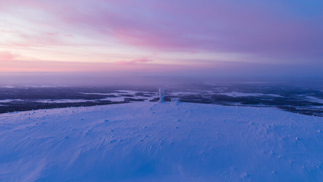 Aerial view of the Luosto fell peak with a weather radar dome under a pink sunset sky in the arctic wilderness of Sodankyla, Lapland, Finland.