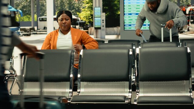 Busy bus station with travelers waiting for express and sleeper bus routes, multicultural passengers with baggage sitting in waiting area before long-distance interstate journey.