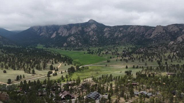 Aerial of rural mountainous residential community in Estes Park Colorado nestled in valley floor in summer with low clouds
