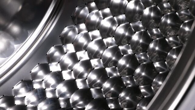 Washing machine drum with honeycomb pattern spinning. Empty washing machine drum with a stainless steel honeycomb texture rotating, seen from the inside pulling back to the front door