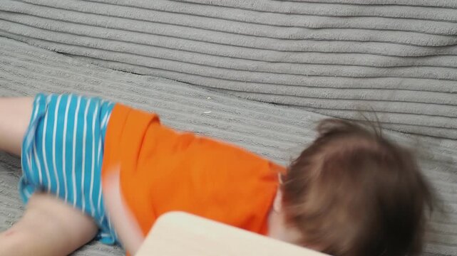 A cute little boy, 2-3 years old, is lounging on the couch, laughing, playing, kicking, misbehaving, and disobeying his mother. Child-rearing challenges