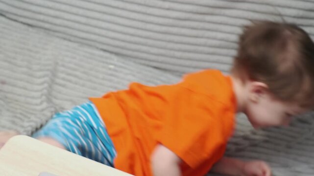 A cute little boy, 2-3 years old, is lounging on the couch, laughing, playing, kicking, misbehaving, and disobeying his mother. Child-rearing challenges
