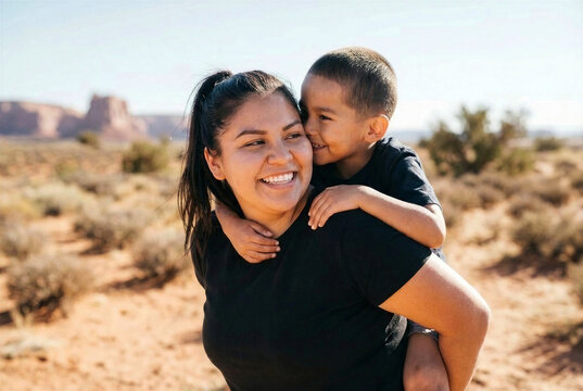 Native American Indian mother carrying her son piggyback in the desert southwest