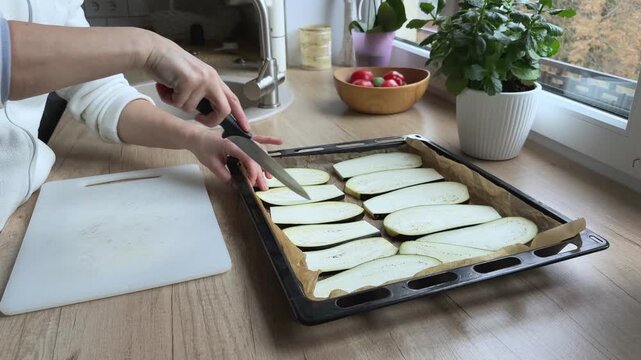 Close angle scoring eggplant slices with knife Preparing vegetables for roasting and baking dish