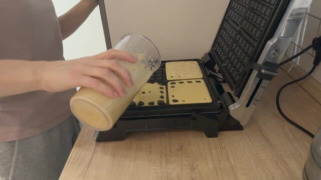 Evenly filling waffle maker grid with batter Preparing homemade waffles baking process breakfast food concept