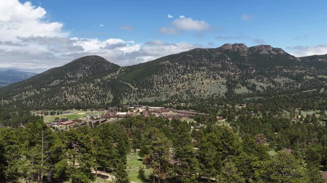 Aerial of lodge and campground nestled among forested in Estes park Colorado in summertime with grassy lawns and cabins