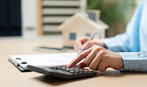 Businesswoman calculating home investment, mortgage costs, and property financing for real estate planning.