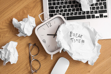 Obraz premium Crumpled paper with text BREAK TIME, alarm clock and laptop on wooden table, top view