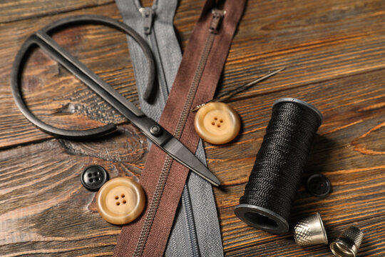Different tailors supplies on brown wooden background