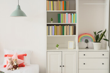 Naklejka premium Interior of light childrens room with bookshelf, bed and toys
