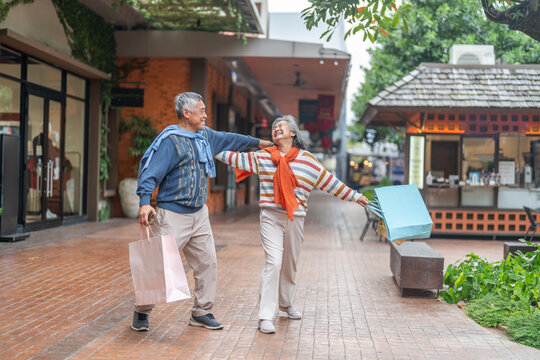 Happy senior asian couple walking and laughing together outdoors, elderly husband and wife enjoying retirement lifestyle and travel in winter, active aging, insurance and health care concept