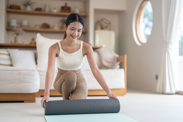 Obraz premium Healthy asian woman unrolling yoga mat preparing for yoga workout, pilates, home fitness concept, wellness, self care, stretching exercise preparation, mindfulness training and active healthy