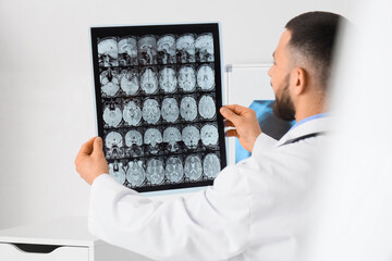 Obraz premium Male doctor with MRI scan of head in clinic, back view