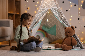 Naklejka premium Cute girl reading adventure book at home in evening