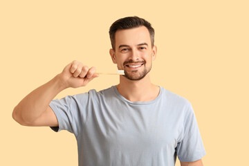 Fototapeta premium Handsome man with toothbrush on beige background