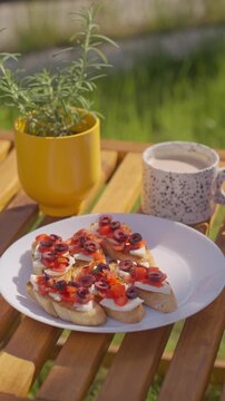 Hand takes bruschetta from a plate on a wooden outdoor table. Concept of simple lunch, summer snack and casual eating