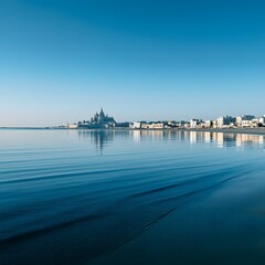Fototapeta premium Coastal City Skyline Reflected on Calm Ocean Water Under Clear Blue Sky