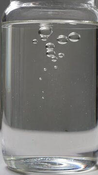 Close-up of clear glass jar filled with water and air bubbles on white