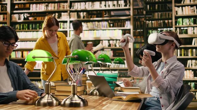 Student using virtual reality headset and hand controllers at library desk, blending interactive digital learning with books and modern research tools, Wearable device for immersive learning.