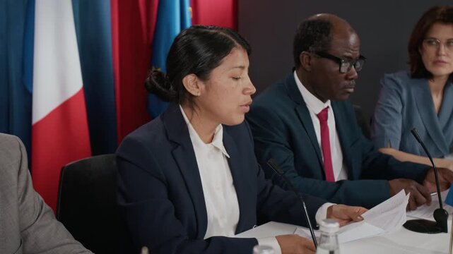 Hispanic young woman speaking at political conference panel next to Black man. Footage is suitable for global politics and corporate communication content