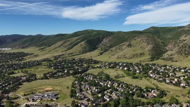 Wide Aerial of Ken Caryl Valley neighborhood in summer in Littleton Colorado with single family homes nestled among green fields and large forested mountainsides