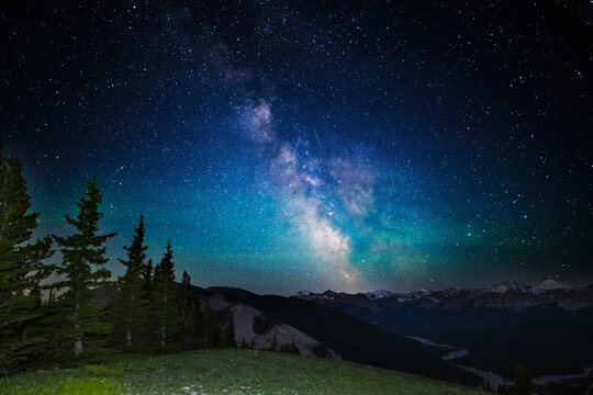 A clear, starry night with the Milky Way in the background, next to a camping tent and the rocky Canadian mountains 