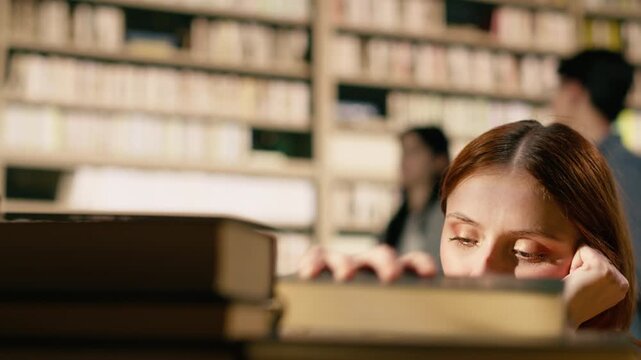 Overwhelmed young woman holding her head near tall stack of books at library table, emphasizing study materials overload and intense exam preparation, Finals pressure study session.