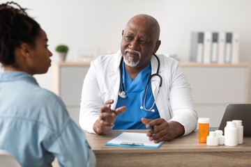 Obraz premium Focused Black Male Doctor Engaging With Young Adult Female Patient During Consultation At Medical Clinic, Discussing Health Concerns And Treatment Options. Healthcare Concept.