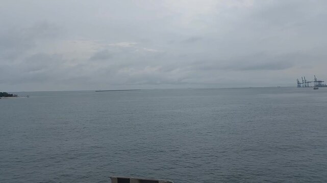 Wide shot from a moving ship traveling across the open ocean near Makassar, Indonesia. Cloudy afternoon seascape with gentle waves and maritime travel and adventure concepts.