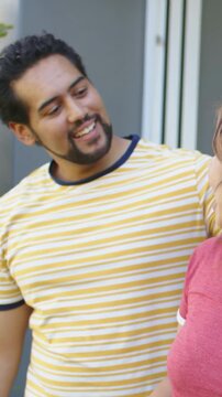 Vertical video: Waving woman turning as man wrapping arm at doorway, striped tee and red tee