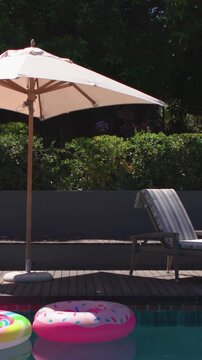 Vertical video: Panning camera revealing light patio umbrella moving left on deck, showing floats