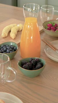 Vertical video: Starting play, panning OJ carafe on home counter while cam zooming to show pancakes
