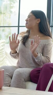 Vertical video: Reacting to pal joke woman in gray sweats turning on home sofa clapping by pink mug