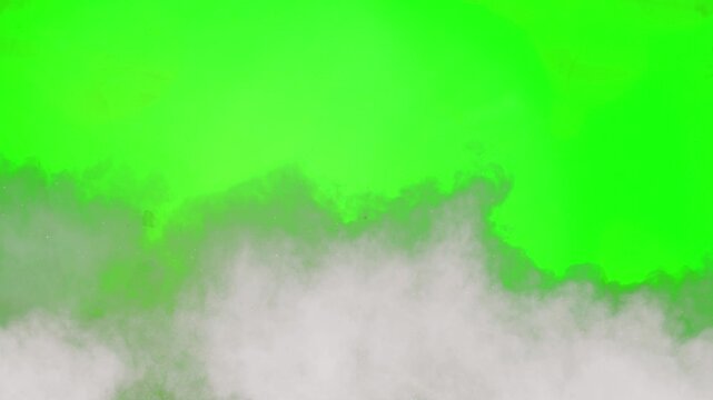 Thick white smoke waves rising across a green screen chroma key background