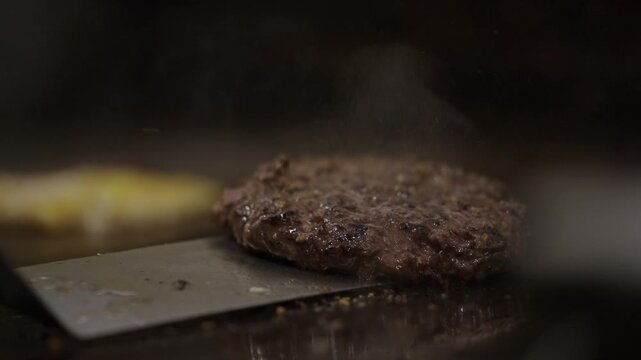 Slow motion burger patties flipped on grill