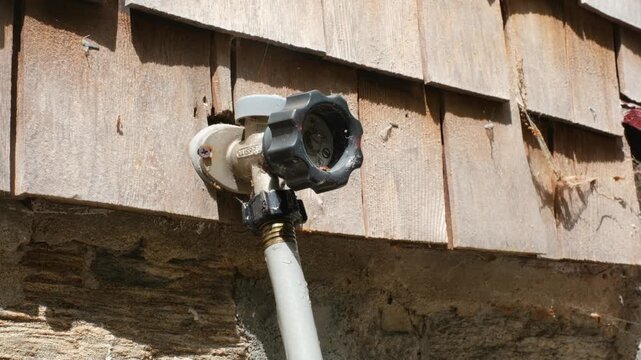 Hand turning off outdoor spicket connected to garden hose