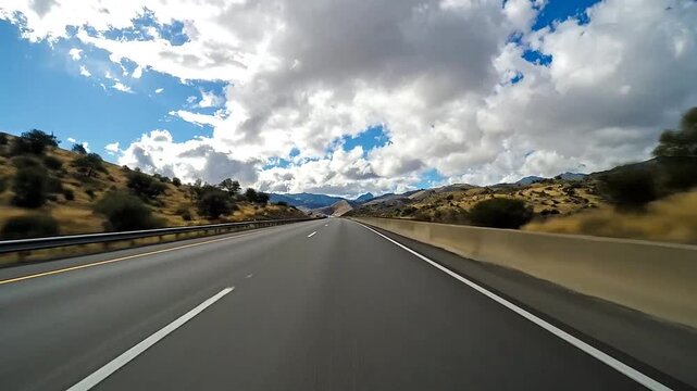 Wide asphalt highway stretches through a scenic mountain landscape
