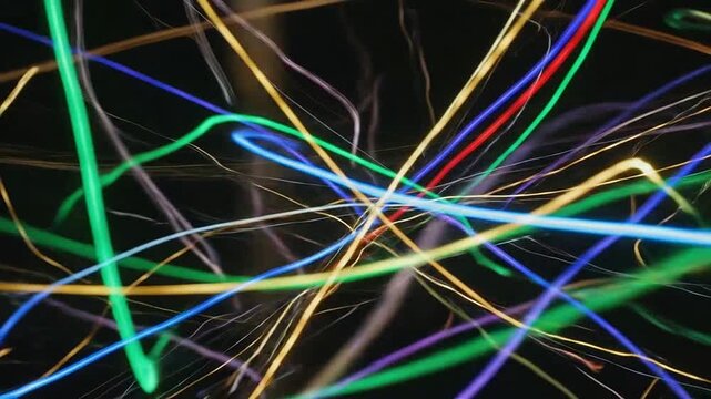 Vibrant neon light trails create an abstract pattern on a dark background