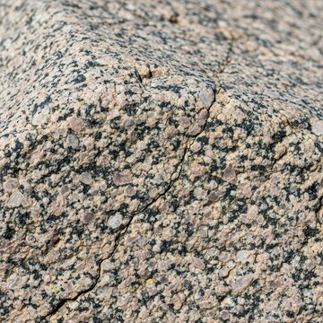 Detailed macro photograph showing the rough, unbreakable surface of a large, ancient granite boulder, symbolizing resilience and lasting power, stable, weathered, wallpaper