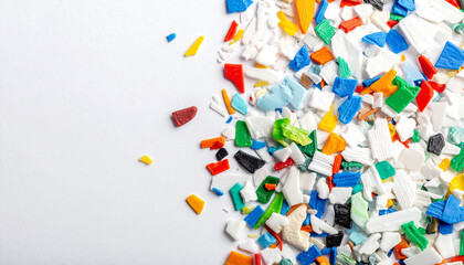Fototapeta premium Colorful Plastic Pellets: A vibrant collection of small, colorful plastic pellets scattered across a white surface, representing material for manufacturing and recycling.